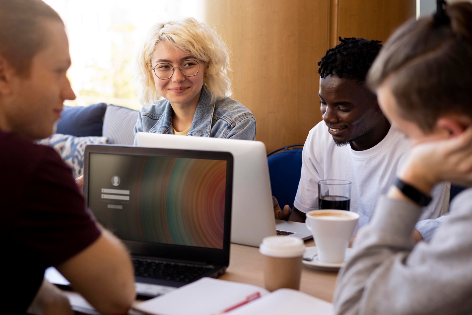 Jeunes adultes souriants travaillant ensemble autour d'ordinateurs portables